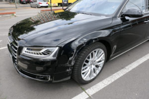 Hier sieht man einen Unfallschaden an einem schwarzen Audi, der Begutachtet werden muss.